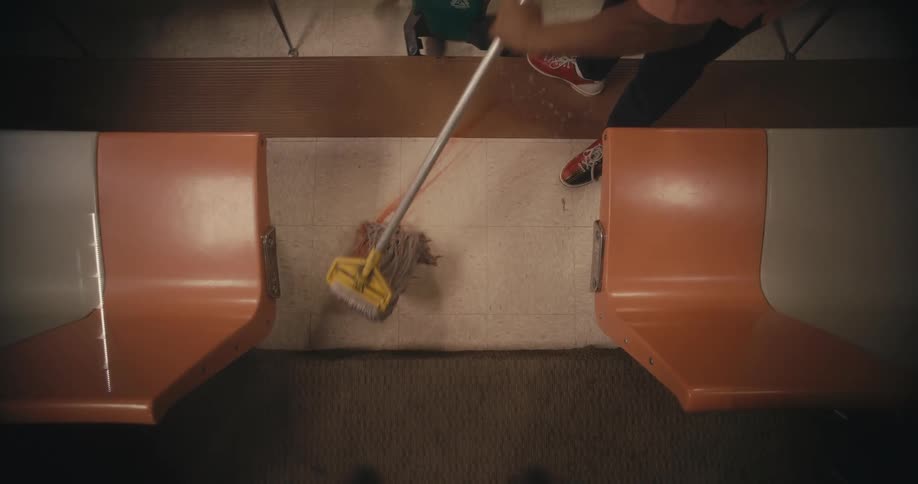 Person mops red liquid staining floor using a string mop