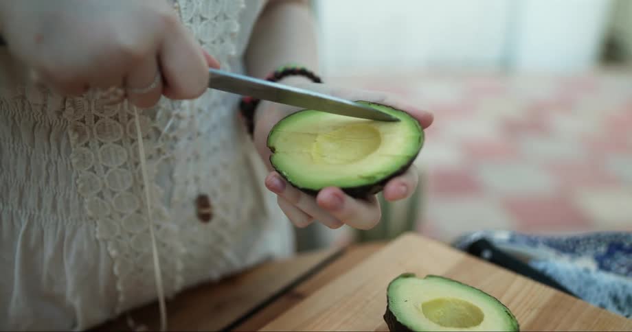A woman is cutting a avocado