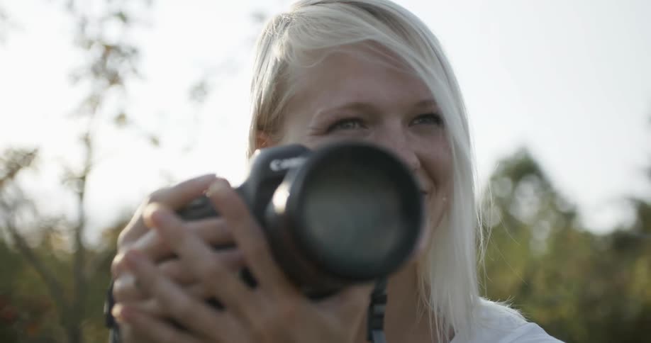 A smiling woman gestures and takes a picture