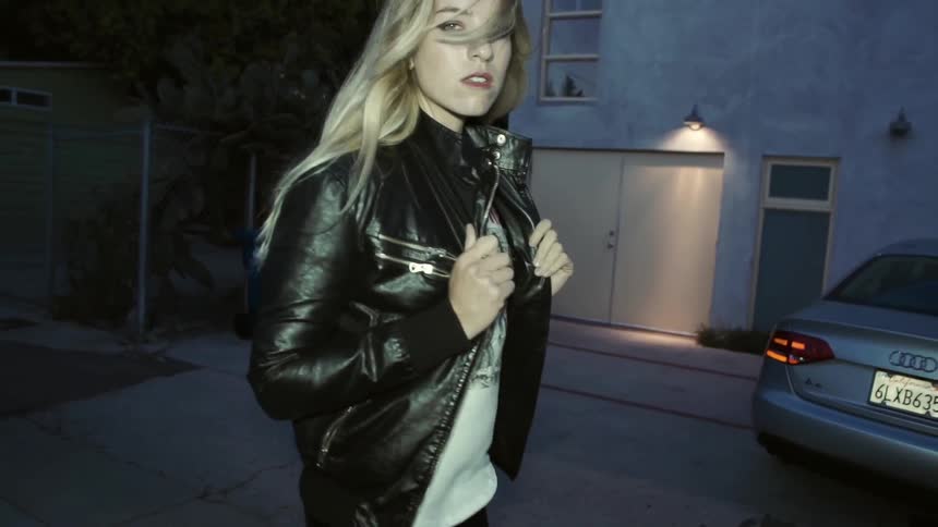 Blonde woman walking sensuously while following the camera in front of her