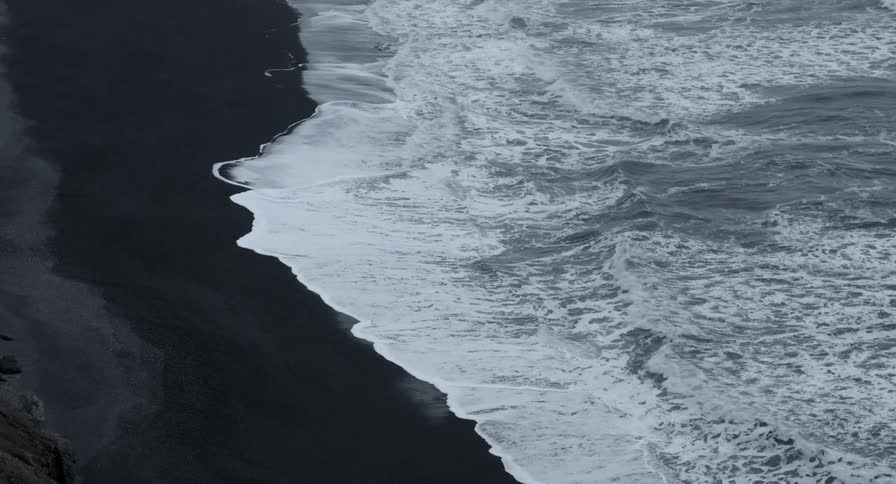 Small waves coming ashore on a dark beach