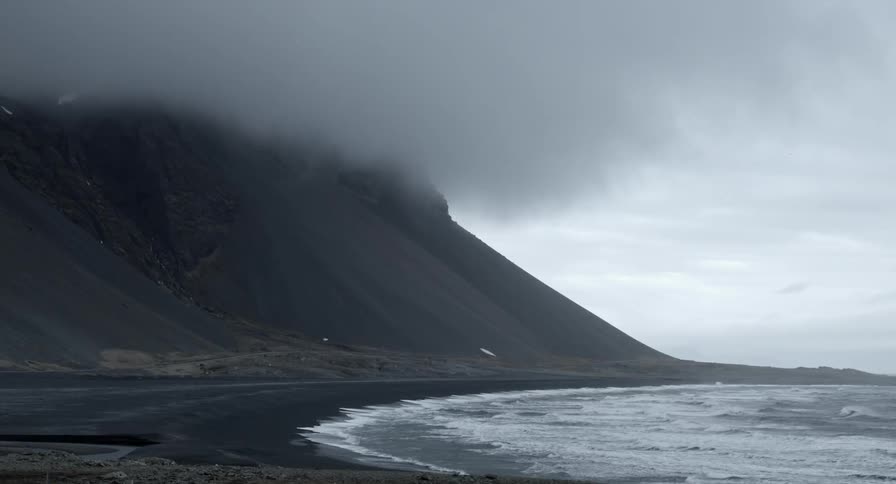 A hillside by the coast is covered with clouds