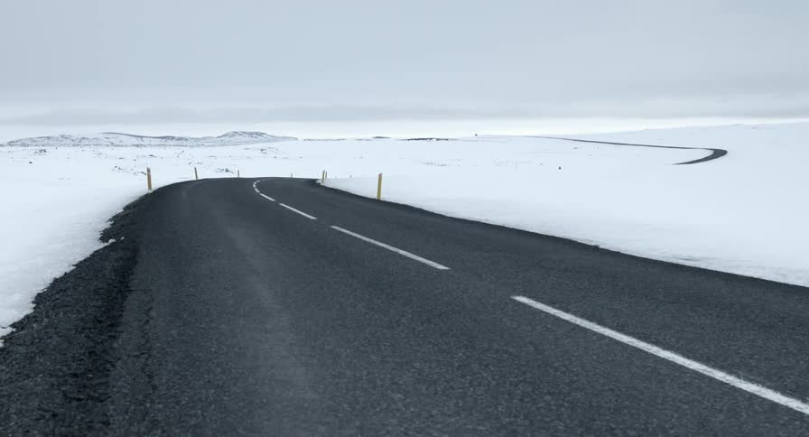 A small empty road is surrounded by snow