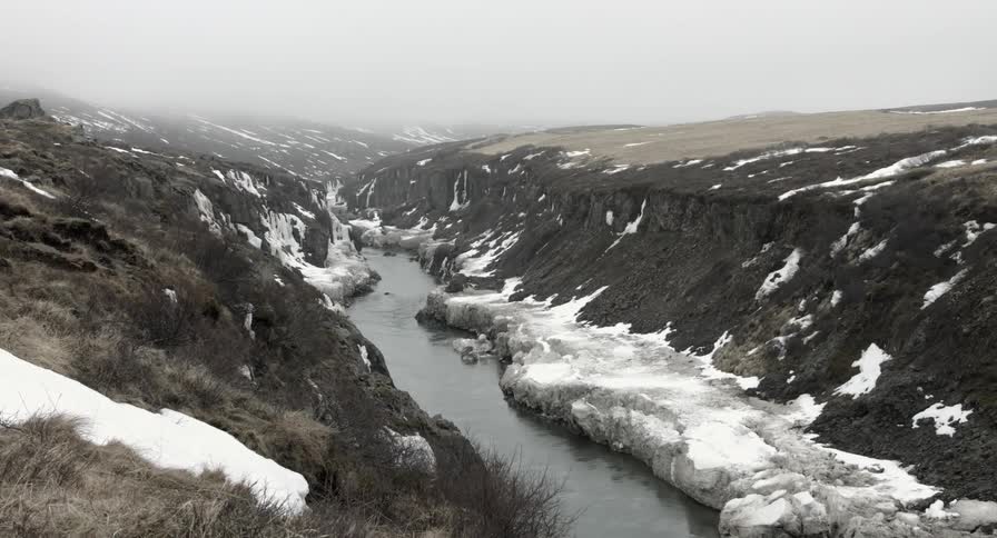 A river through a snowy area on a cloudy day