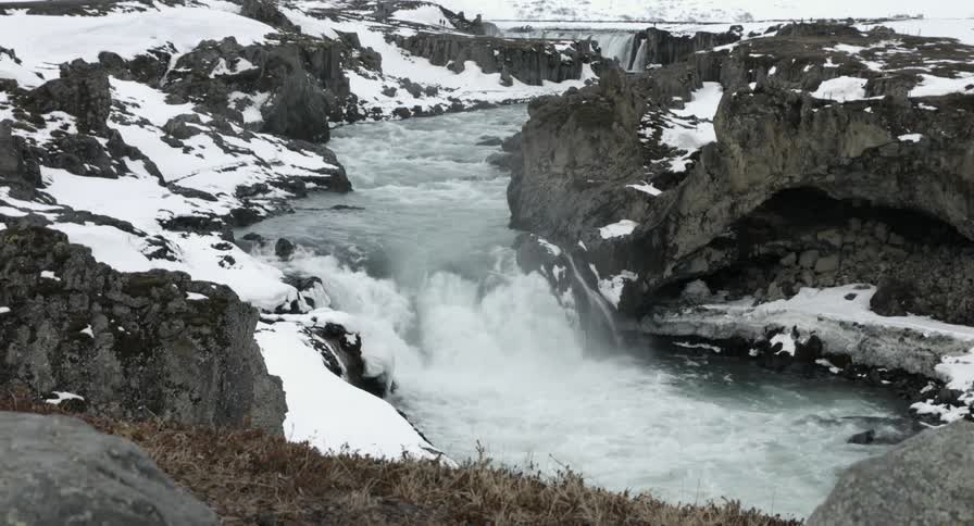 Water flows down a small drop between rocks in an icy stream