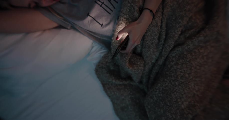 A woman is laying down and looking at a cellphone