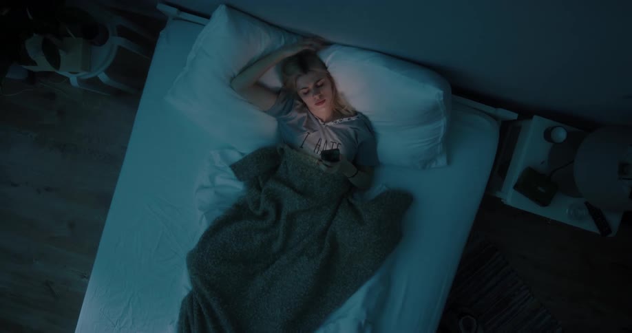 A woman laying in a bed with a smartphone