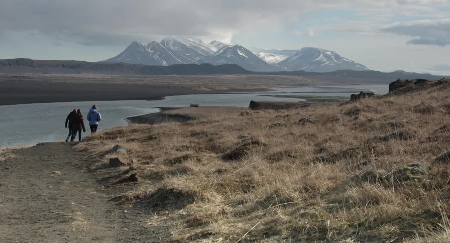 Three people walking a path along the water's edge