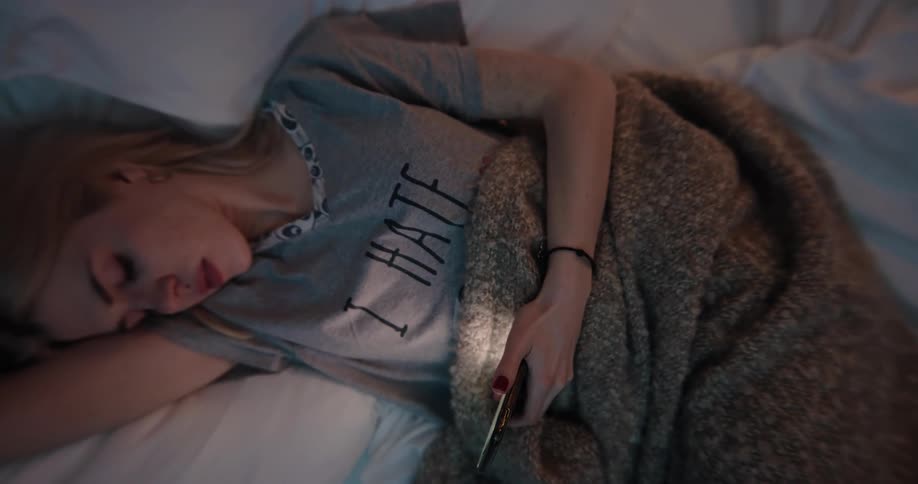 A woman is laying down and texting on a phone