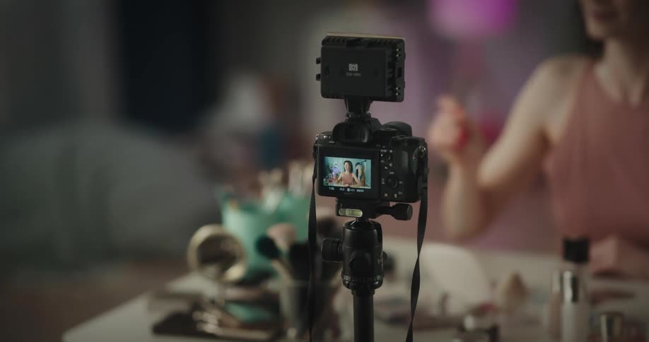A woman applies make up in front of a camera