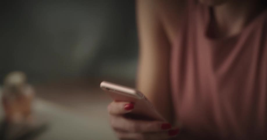 Woman sitting at a table reading on a smartphone on her hand
