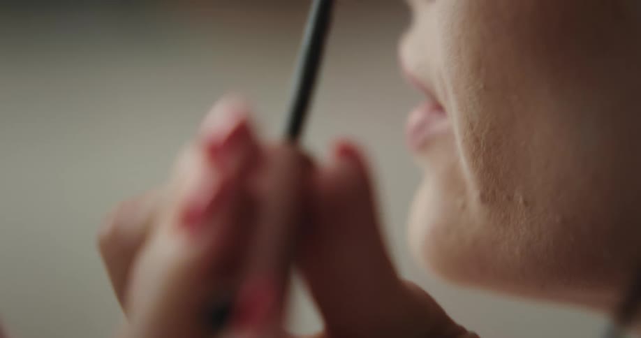 A woman is putting on makeup indoors