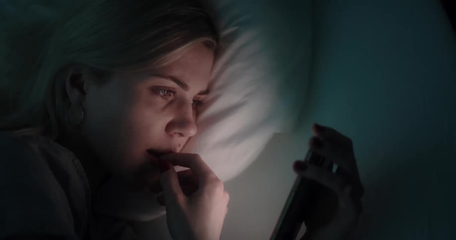 A woman is texting on a phone while laying down