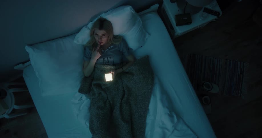 A woman is laying in bed and texting on her phone