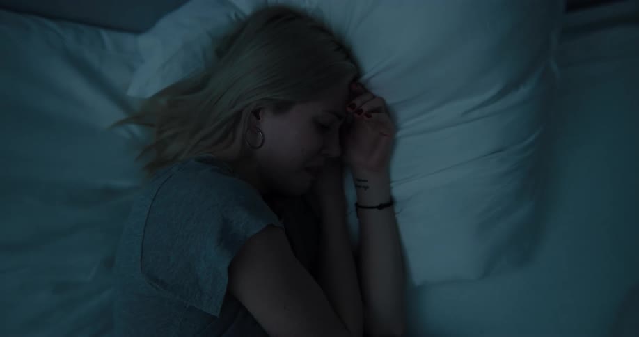 A woman is crying as she lays in bed