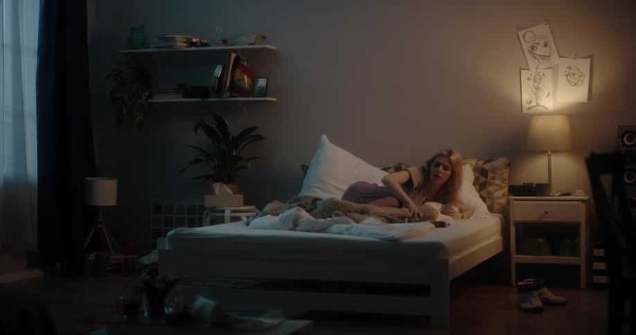 A woman turns the lights off to go to sleep in bed