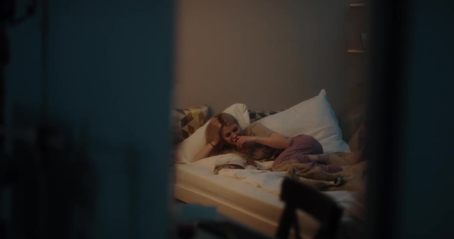 Young woman lying in her bed while leafing through a magazine