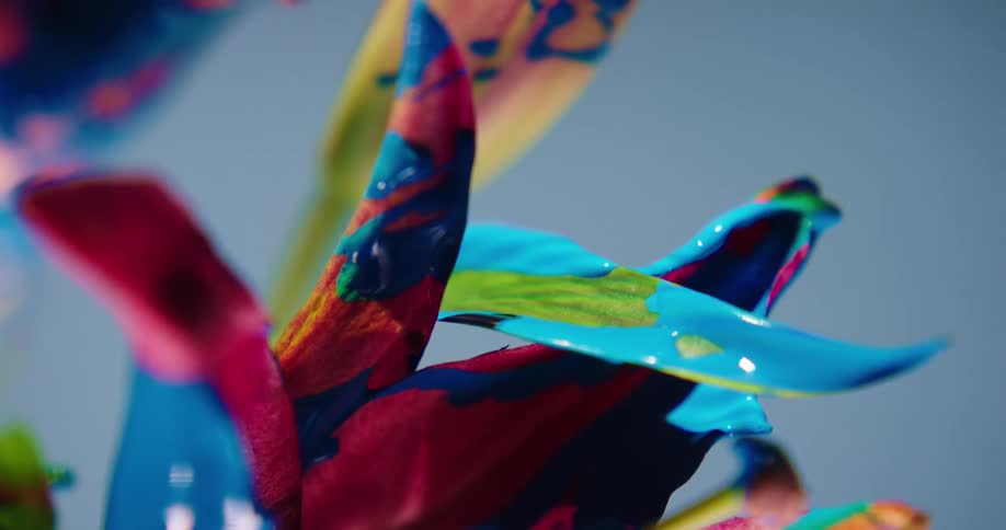 Colorful rainbow liquid glitter shimmering ink drips sideways from a flower