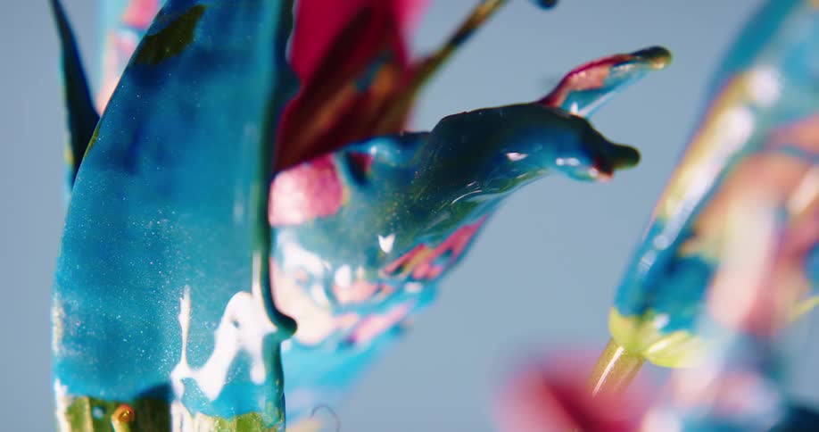 An insect flies past a plant covered in blue dripping paint
