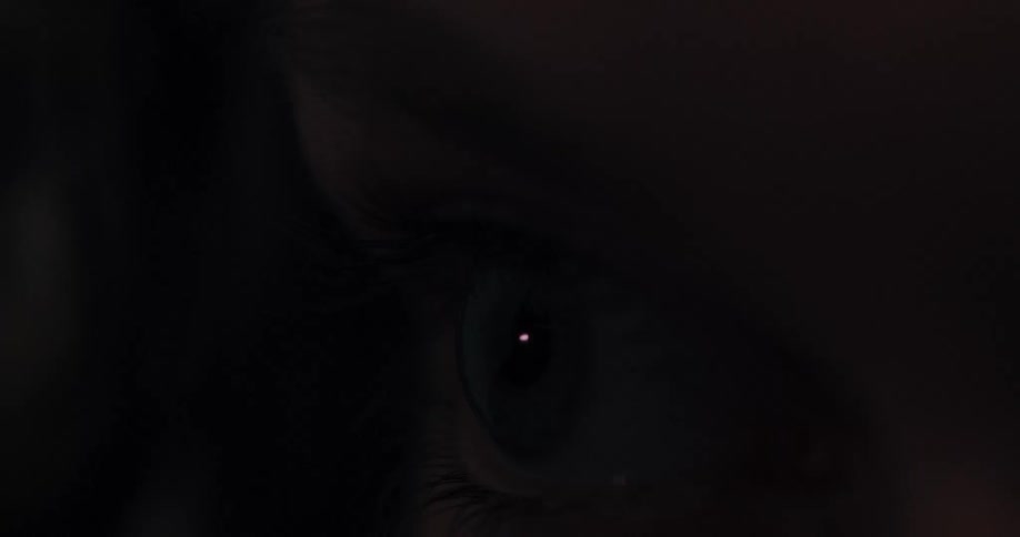 A person blinks in the dark