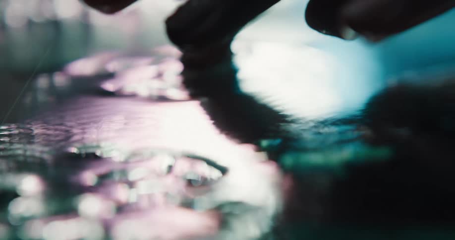 A woman taps her fingers in a puddle on the ground