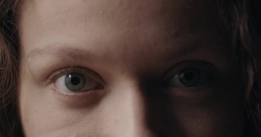 Woman with wavy hair opens eyes and stares at camera