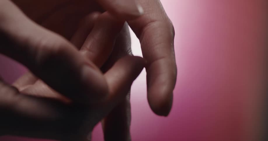 A persons hands and fingers moving up and down and gently touching each other in front of a pink background