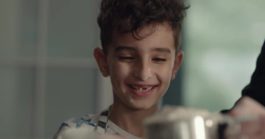 A boy pours flower in the kitchen