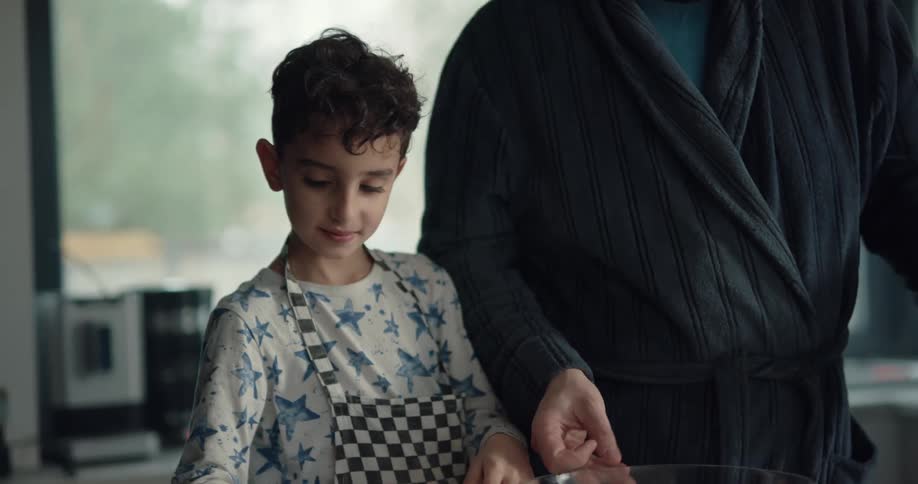 Father and son each break an egg into a large bowl then the son pours milk into the bowl