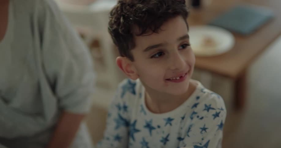 A woman laughs after stopping her son from licking jam out of the jar