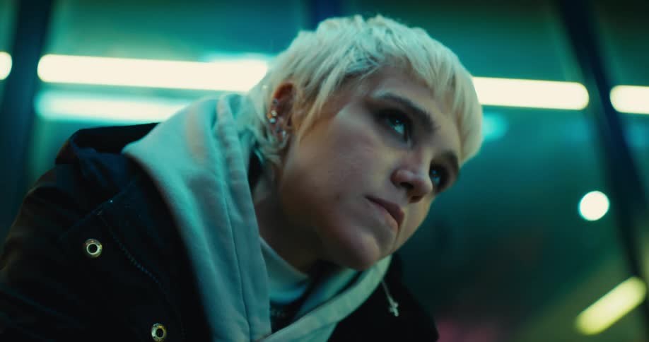 Young anxious woman nervously waiting while sitting inside a laundromat at night