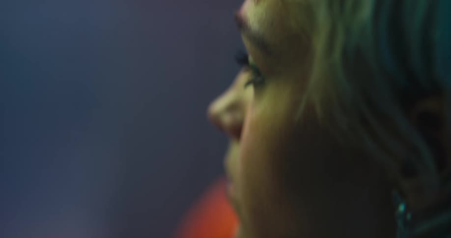 A woman is sitting indoors on a chair at night