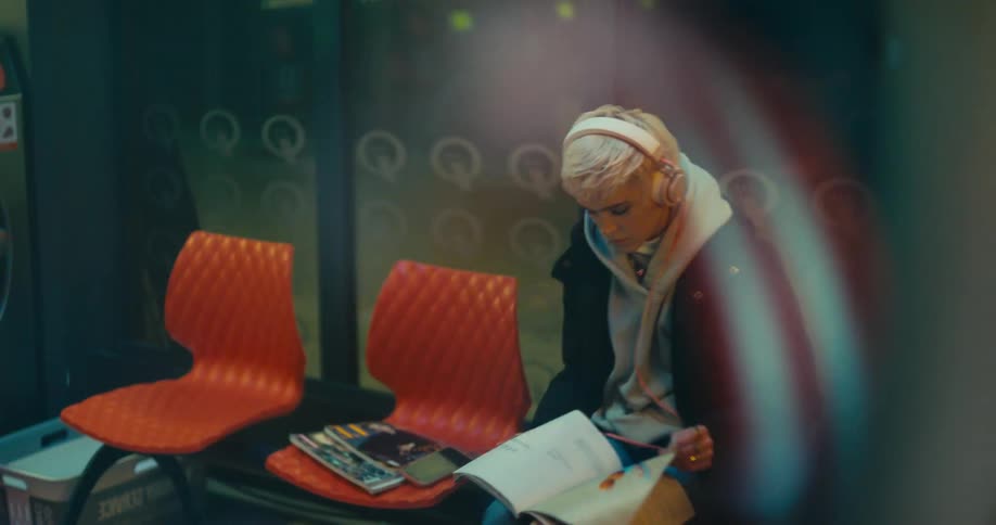A woman is sitting indoors and reading a magazine