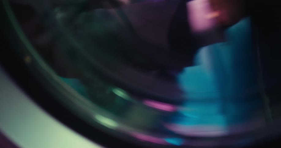 A woman is putting clothes in a dryer machine