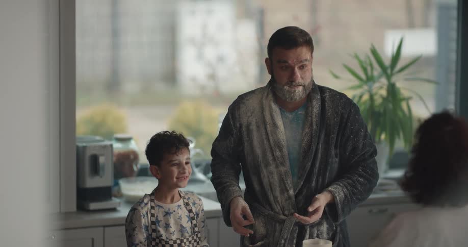Father and son throw flour at each other then blame each other when the mother walks in