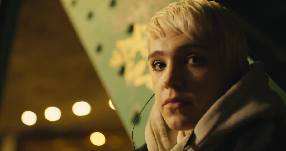 Young blonde woman with short hair turns her head to look at the camera