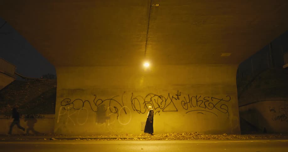 Woman walking under bridge has her purse stolen and then sits against concrete wall