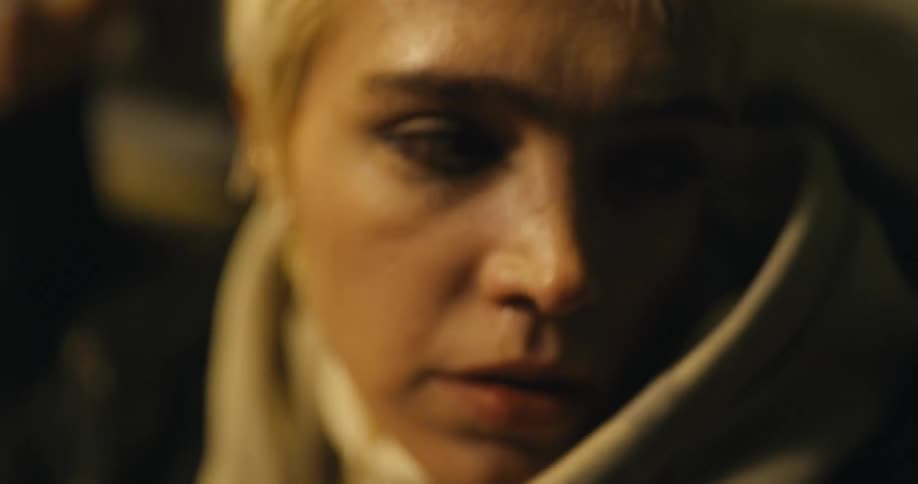 A woman wipes tears from her face and runs her hand through her hair looking around anxiously