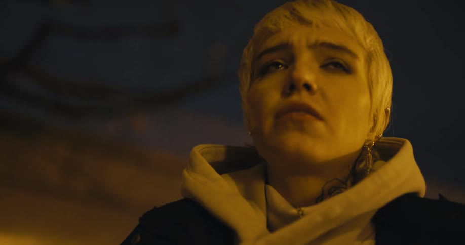 Young anxious woman nervously uses her phone near an overpass in the city at night