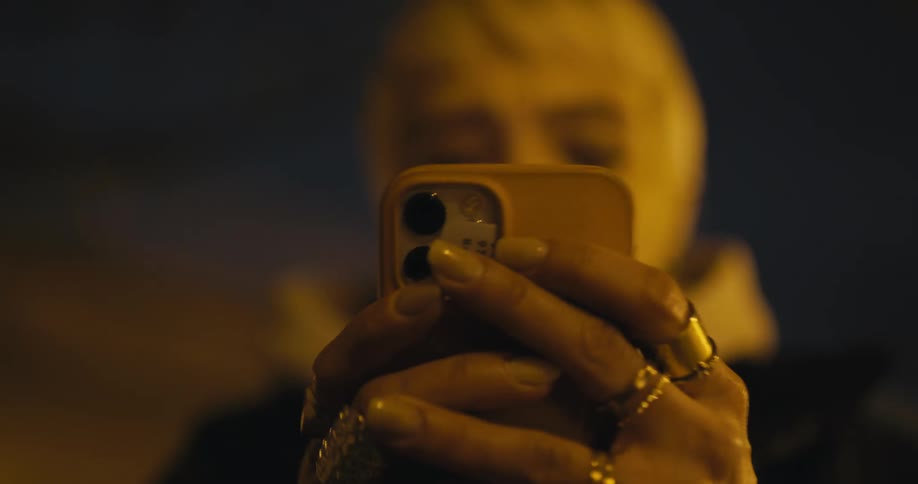 A woman pulls out her phone at night