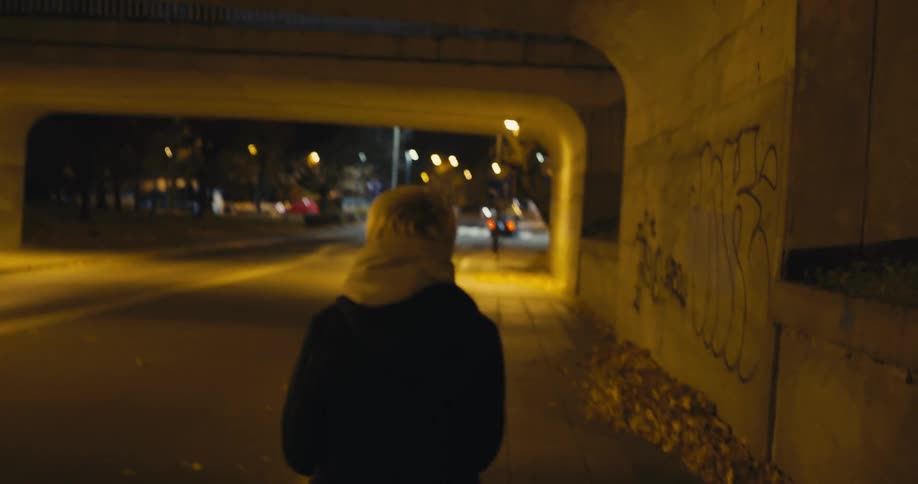 A woman looks around nervously as she travels under the overpass