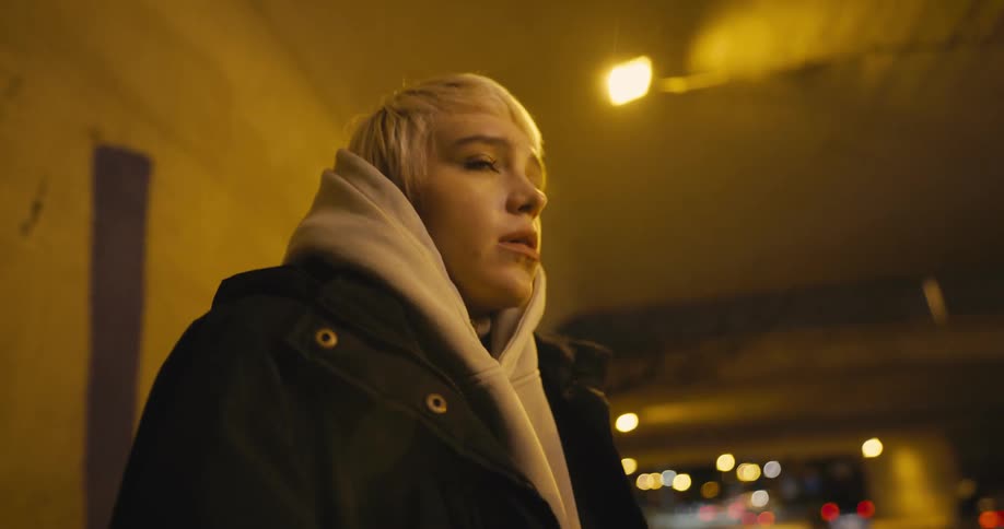 An anxious young female smoking in a freeway underpass