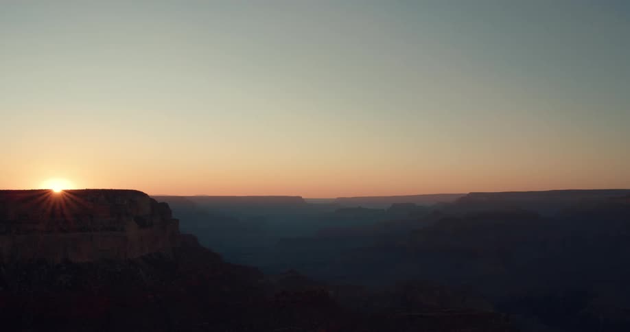 Sun sets over plateau in foggy canyon country