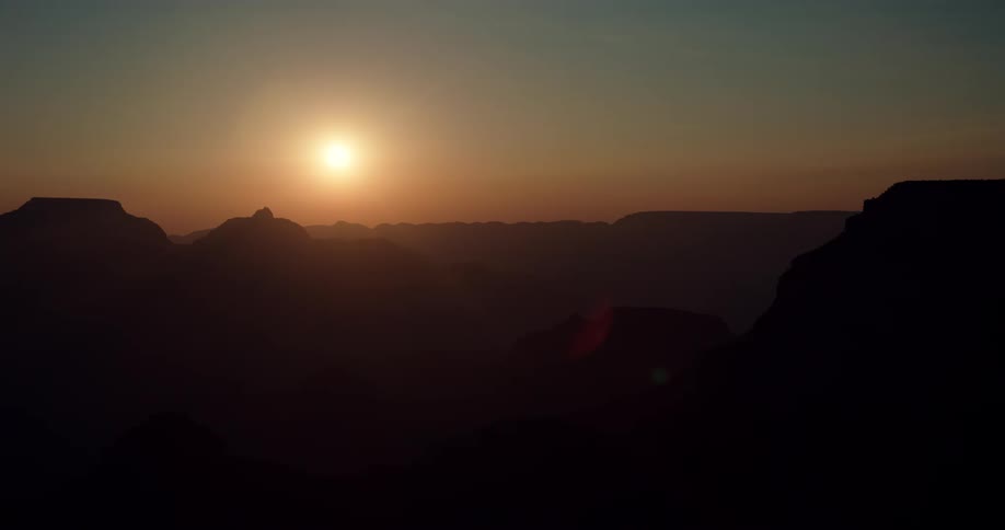 A canyon at dusk with the sun setting in the background