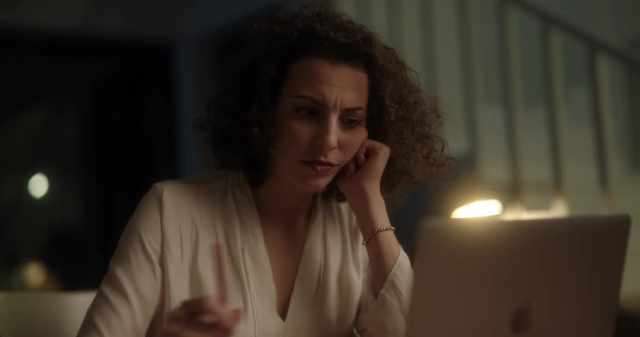 Woman writes with a pen on a paper then looks at her laptop