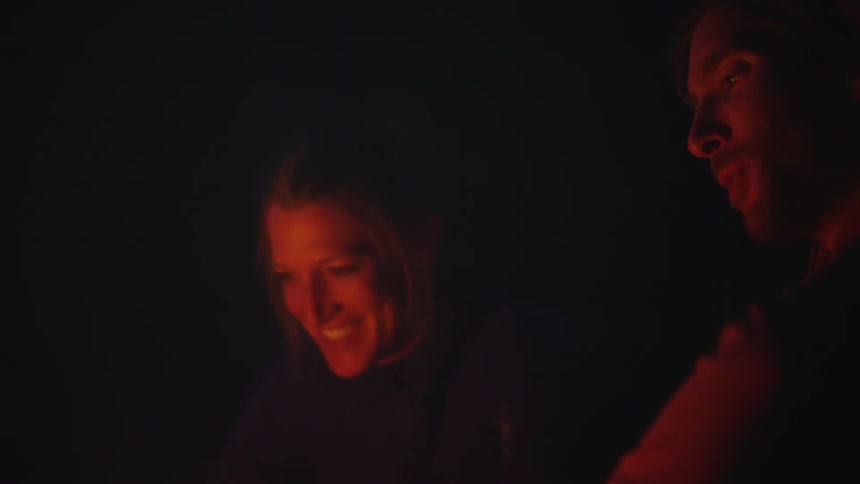 Two people talk by the campfire
