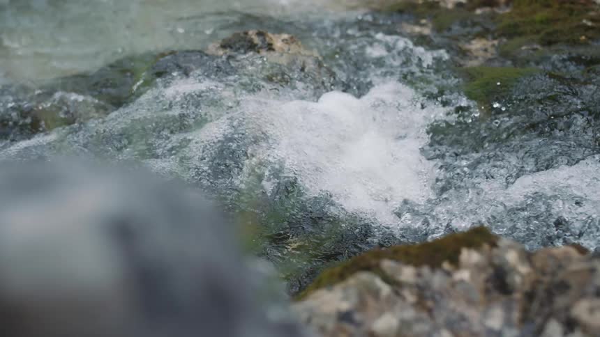 Close up of the turbulence on the surface of a gentle creek flowing over the rocks on a river