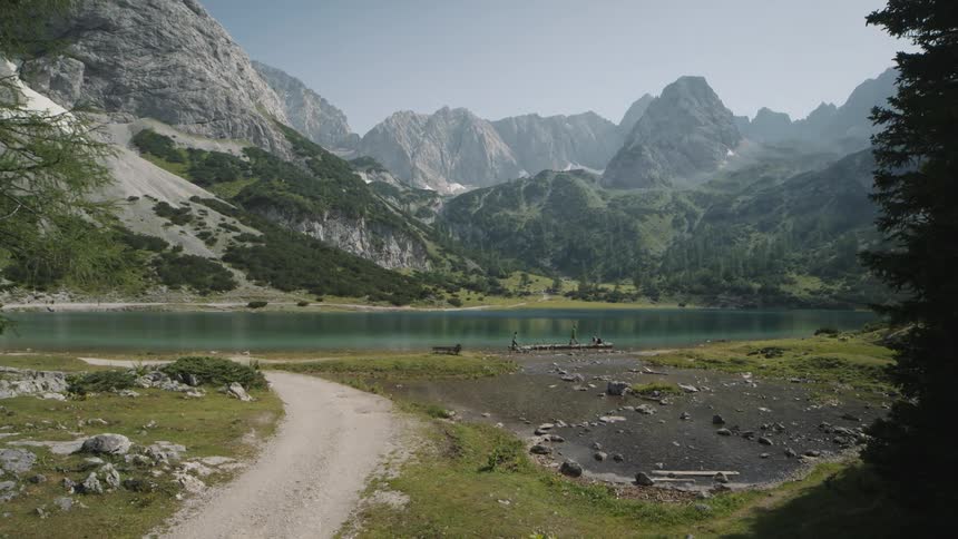 A dirt road leads to a lake below a mountain