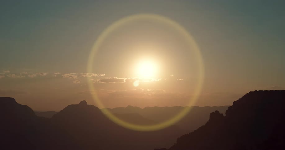 Silhouettes of rock formations and mountains as the sun shines and creates a halo