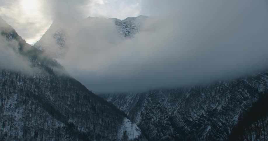 Snow covered forested mountains under a cloudy sky